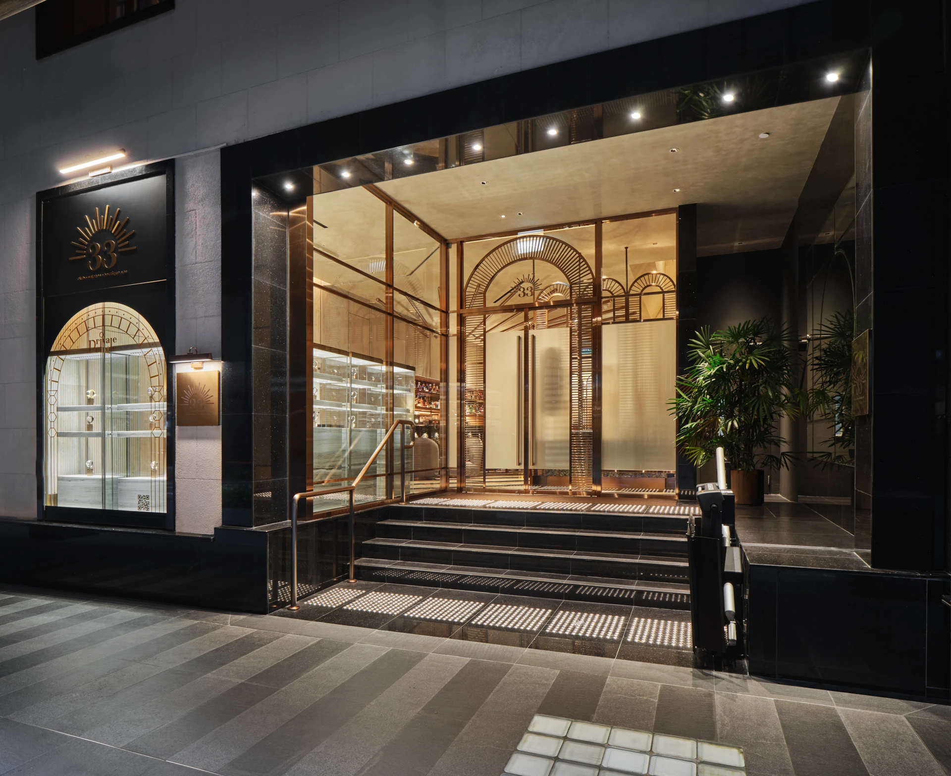 Art Deco entrance with black granite, sunburst brass logo and copper rails