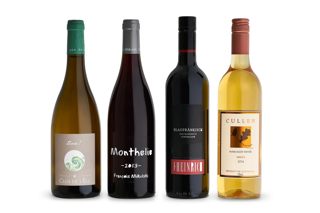 Four wine bottles in a row on a white background: Clos de l'Elu white, Monthelie 2013 red, Blaufrankisch red, and Cullen Amber 2014.