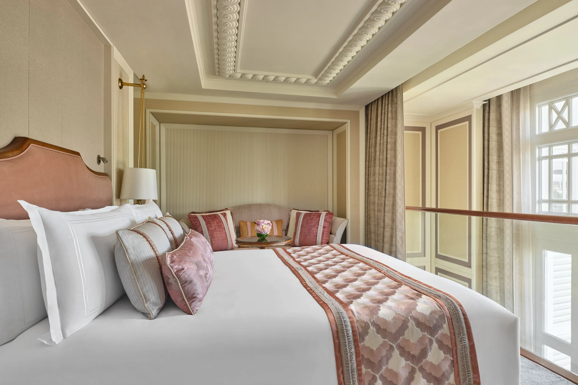 Coral bedroom with scallop throw, velvet cushions and brass reading lamp