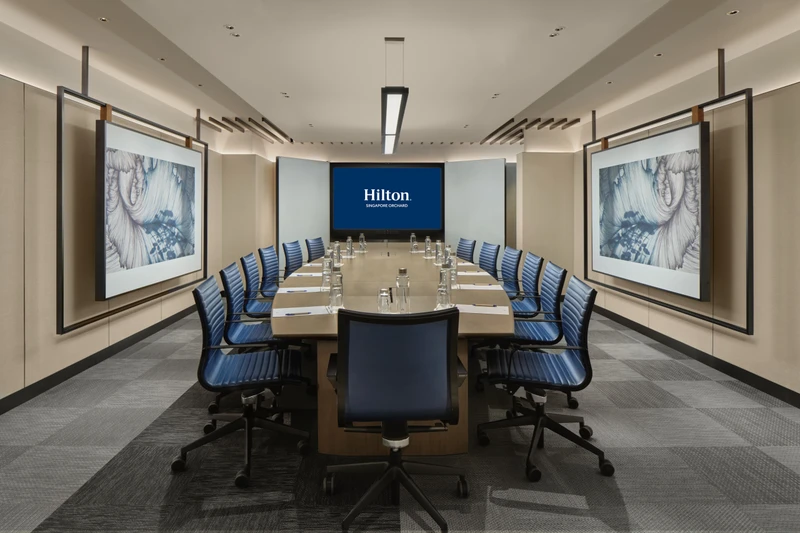 Level 5 Ficus boardroom at Hilton Singapore Orchard with blue banquette seating, long meeting table and framed wall art