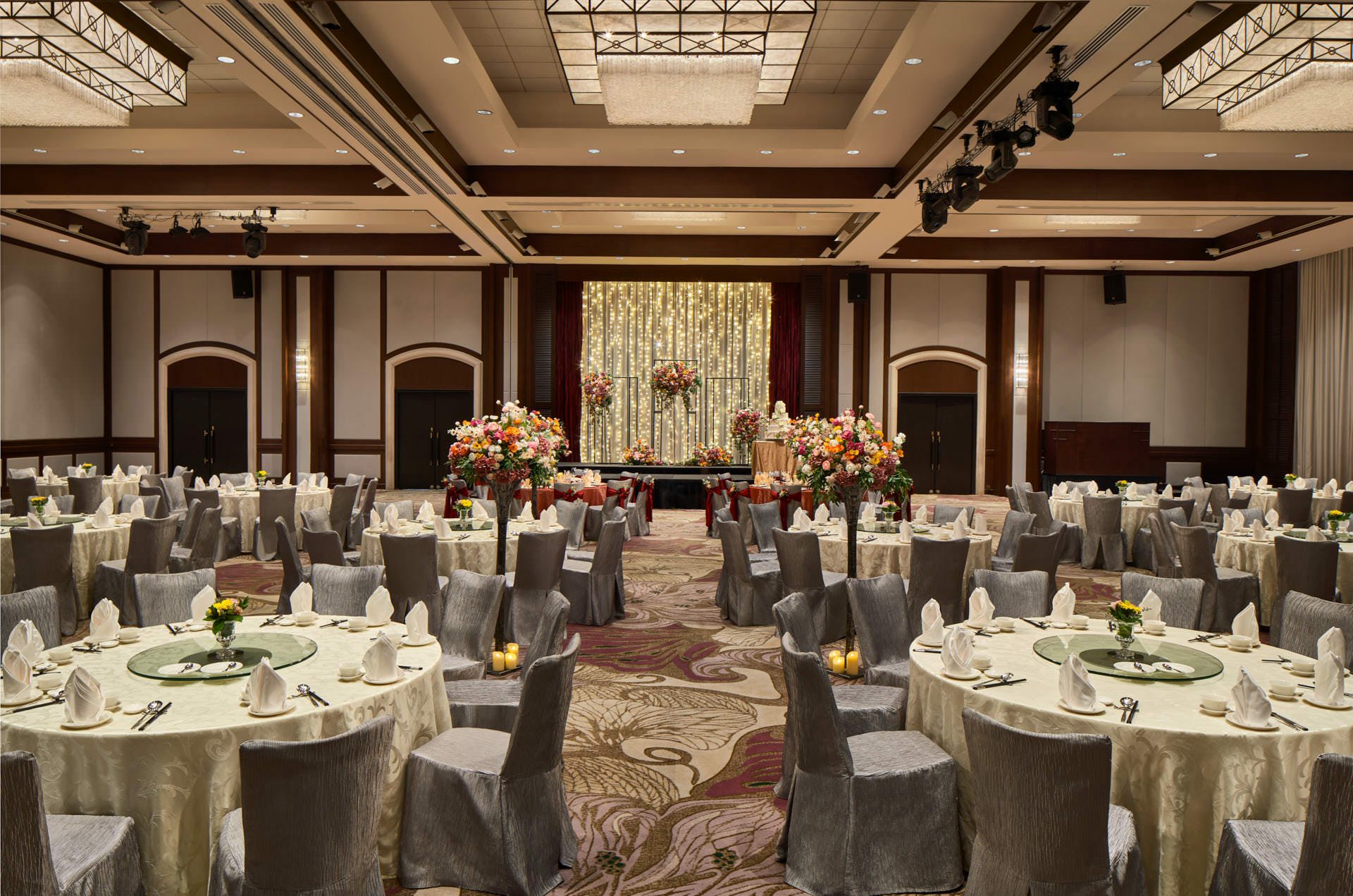 Paradox Singapore ballroom wedding banquet with ivory linens, floral aisle, and fairy-light backdrop