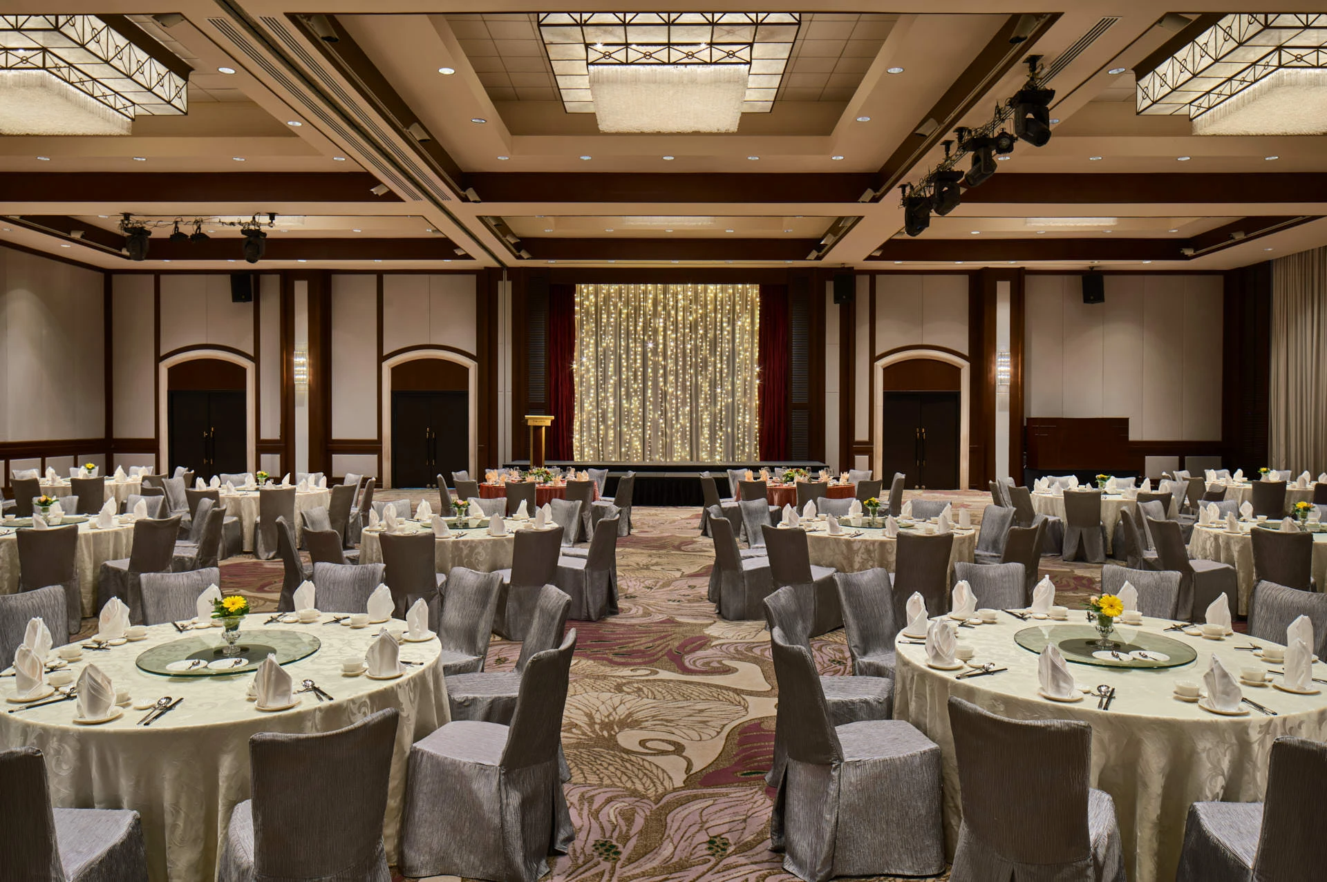 Paradox Singapore dinner and dance banquet with silver chairs, floral centrepieces, and fairy-light stage