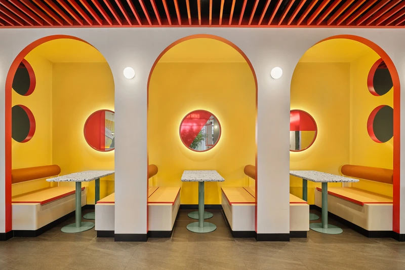 Yellow arched booth alcoves with porthole windows and globe sconces at PastaMania Northpoint
